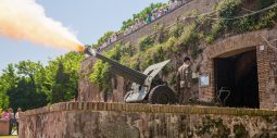 Il Cannone del Gianicolo firing its daily noon blank round with a burst of flame, watched by tourists from the terrace above, Rome